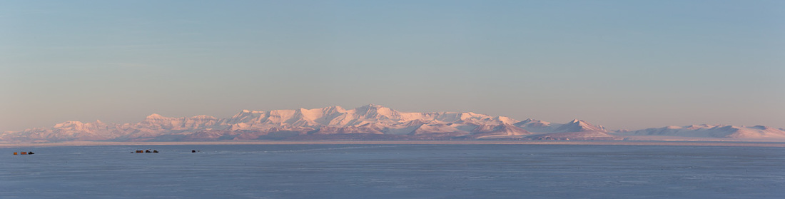 View across sea ice to mountain range.